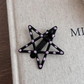 Dettaglio di un fermaglio per capelli a forma di stella con pois rosa su base nera - Stile a pois stella