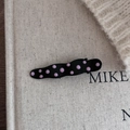 Dettaglio di un fermaglio per capelli nero ondulato con pois rosa 3D su sfondo materico - Stile a pois ovale irregolare