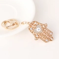 Gouden Hamsa hand sleutelhanger met kristallen boze oog en hart op wit dienblad - Wit