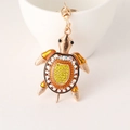 Porte-clés tortue dorée avec cristaux jaunes et émail orange sur fond blanc - Jaune