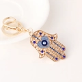 Gouden Hamsa hand sleutelhanger met blauw boze oog hart en sprankelende strass steentjes - Blauw