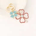 Golden clover keychain with pink and blue rhinestones featuring a secure lobster clasp - Red