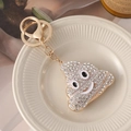 Golden sparkling emoji poop keychain with rhinestones and lobster clasp on ceramic plate - White