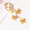 Modieuze gouden vlinder sleutelhanger met oranje emaille hangers en ronde H-bedel - Geel