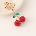 Porte-clés cerise rouge scintillant avec strass et détails dorés sur socle blanc - Porte-clés Rouge