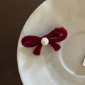 Detail of red velvet bow hair clip with center pearl on a ceramic tray macro view - Red Bowknot With Artificial Pearl