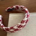 Detail of tweed headband with 'HAND MADE' label on a vintage wooden background - Red White Argyle