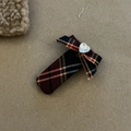 Detail einer karierten Haarschleife mit herzförmigem Strassstein und britischem Preppy-Stil - Dunkel gestreifte quadratische Schleifenspange