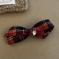 Close-up of a plaid bow hair clip featuring a sparkling heart crystal and British pattern - Red Stripe Cross Bow Style