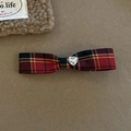 Close-up of British style red plaid bow hair clip with a heart shaped crystal center - Symmetrical Long Bow Clip