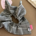 Detail of checkered fabric scrunchie with floral shell button and pink logo label - Style 2 Black and White Plaid Windmill Scrunchie