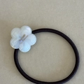 Nahaufnahme der weißen Acetat-Blume mit Perlmutt-Glanz auf schwarzem elastischem Haargummi - Transparente Weiße Blume