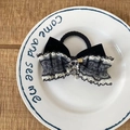 Elegante pinza de terciopelo negro con lazo de encaje y borla dorada en un plato blanco - Coletero de Lazo a Rayas Azules