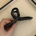 Detail view of the glossy black twisted hair claw clip being held to show grip and texture - Dark Brown Cross Hair Claw