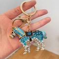 Pferde-Schlüsselanhänger mit blauen Strasssteinen und goldener Legierung auf der Hand - Blau