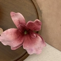 Detailaufnahme einer rosa Orchideen-Haarklammer mit Samttextur auf Holztablett - Burgunderrot
