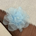 Nahaufnahme hellblauer Blumen-Haarclip aus Tüllschichten auf dunklem Holztisch - Blau
