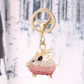 Golden alloy flying pig keychain with pink rhinestones and white enamel accents - Pink White