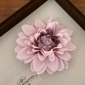 Dettaglio del fermaglio per capelli a fiore rosa con petali in tessuto su sfondo beige - Viola