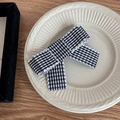 Close-up of black and white checkered bow hair clip with textured wavy edges on a ceramic plate - Black White Grid