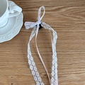 Detailed macro of a light pink lace bow hair clip with long ribbons on wooden surface - Pink
