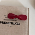 Elegante fermaglio per capelli a fiocco rosso scuro su un libro per un look retrò raffinato - Fiocco rosso