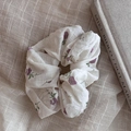 Florales weißes Haarband mit lila Blumen auf beigem Leinen neben einem Kunstbuch - Lila Blumendruck Scrunchie