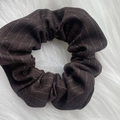 Detail of a brown plaid scrunchie with golden metallic threads on a plush white surface - Khaki Striped