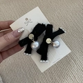 Detail view of black velvet bow earrings with grey pearls and golden metal accents - Black Bow Outfit