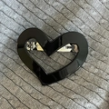 Dettaglio di un fermaglio per capelli nero lucido a forma di cuore su maglia grigia - #4 Clip A Molla A Forma Di Cuore Nera