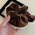 Dettaglio della texture di un elastico in velluto marrone con bordo di perle bianche - Cachi