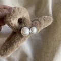 Detail of large brown plush hair claw clip with two white pearls held by hand - Coffee