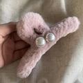 Close-up of pink plush claw clip with white pearls on a grey linen background - Pink