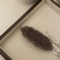 Nahaufnahme einer braunen Teddy-Plüsch-Haarspange mit weicher Textur auf Holztablett - Kaffeebraun