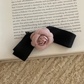 Détail de la pince à cheveux en satin noir avec fleur de camélia rose sur livre - Nœud Noir Avec Fleur Rose