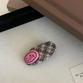 Dettaglio di un fermaglio per capelli in tweed marrone con targhetta rosa e scritta Cute - Strisce Bianco Tè al Latte (Patch Rosa)