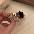 Detail showing handcrafted rainbow knitted hair tie with golden bead and velvet flower - Off-white Coiled with Black Bear