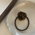 Detail van een amberkleurige camelia bloem haarelastiek op een wit keramisch bord - Blauwe Schildpad Bloem