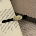 Pince à cheveux vintage en velours noir avec plaque dorée ovale sur un livre ouvert - Pince bec de canard à plaque ovale dorée