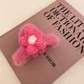Handmade pink plush hair claw clip with woven floral detail on a fashion book - Rose Red Flower Plush Style
