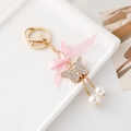 Llavero con lazo rosa, mariposa de diamantes de imitación y perlas blancas suaves - Rosa Claro