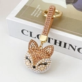Champagne fox keychain with rhinestones and pearls on a white book backdrop - Champagne