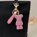 Pink rhinestone bear keychain with matching hand strap on a black canvas bag - Pink