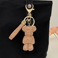 Sparkling champagne gold rhinestone cartoon bear keychain attached to a black fabric bag - Champagne