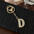 Elegante portachiavi lettera D dorata con strass scintillanti su pelle nera - Lettera D