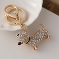 Golden dachshund keychain with clear rhinestones and lobster clasp on white plate - White