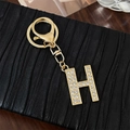 Golden alloy keychain with letter H pendant inlaid with sparkling white crystals - Letter H