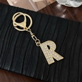 Elegant gold-tone letter R keychain pendant with sparkling rhinestones on black background - Letter R