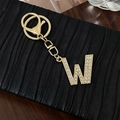 Golden alloy letter W keychain with sparkling crystal rhinestones on a leather background - Letter W