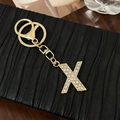 Sparkling gold alloy letter X keychain pendant with crystals on a textured background - Letter X